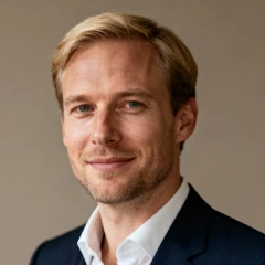 Porträt eines Geschäftsführers im Anzug vor neutralem Hintergrund.